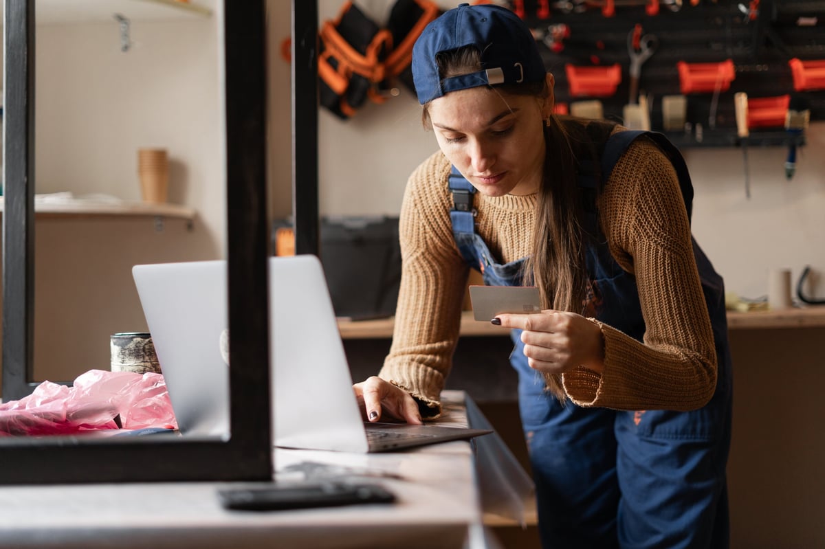 Craft workshop owner with tools using laptop and credit card for online purchases and contactless payments. Concept e-commerce, internet banking, small business management, and digital finance